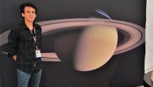 Sahand Sabet standing in front of a picture of Saturn on the NASA campus