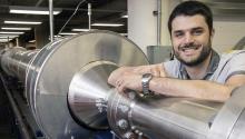 Alex Craig smiles and rests his arm on a 104-foot silver wind tunnel.
