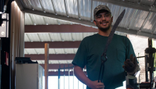 Mechanical engineering student Chuy Talavera stands in a garage holding sword