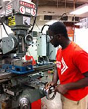Engineering senior Rolland Prempeh perfects a component for his senior design project on a mill in the AME machine shop 