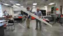 Aerospace engineering doctoral student Adrien Bouskela (left) and aerospace and mechanical engineering professor Sergey Shkarayev holding a sailplane in a lab