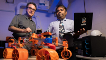 Jekan Thanga and Moe Momayez in a lab with a 3D-printed rover.