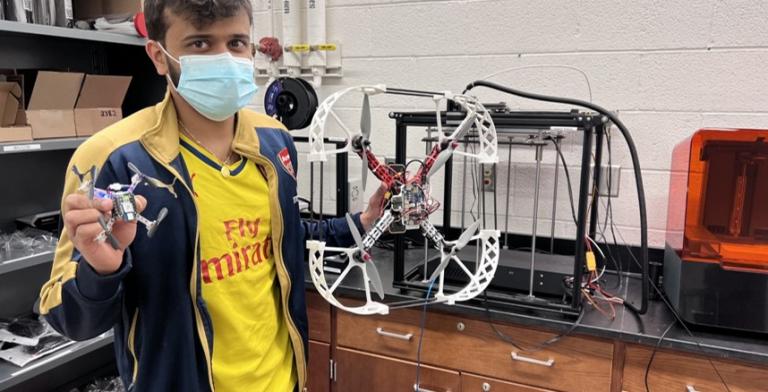 A student holding a drone in a lab.