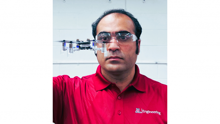 Hossein Rastgoftar wearing safety goggles, with a drone hovering in front of his face.