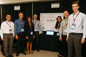 UA Hyperloop team with adviser Cho Lik Chan in front of their poster in Texas