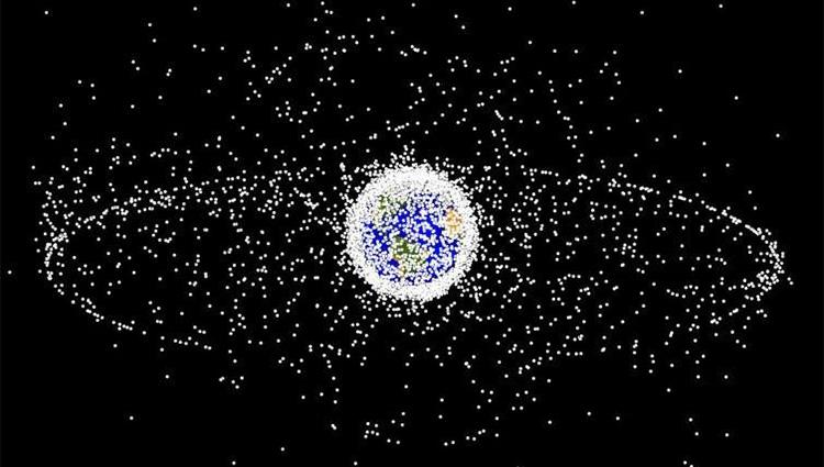 Illustration of the Earth surrounded by white dots representing space junk. Most dots are concentrated close to the the earth in a tight cloud, though a second ring of dots appears farther out.