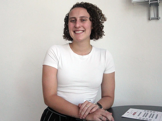 A woman with curly brown hair poses for a photo.