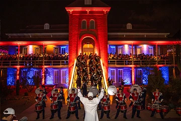 Univ of Arizona Old Main building lit up, nighttime, with marching band