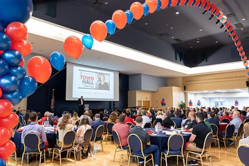 ballroom with attendees seated under an arch of balloons