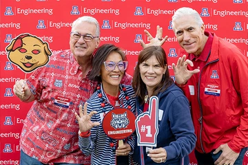 four people smiling, holding Univ of AZ swag