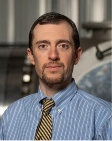 portrait photo of person in blue striped shirt with brown tie