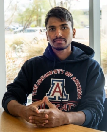 person wearing blue hooded sweatshirt, hands folded on table