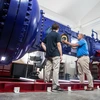 Two men handle parts of a major wind tunnel.