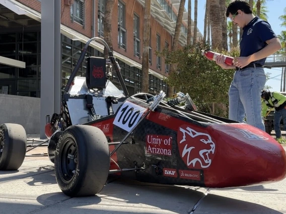 Aerospace and mechanical engineering junior Cooper Graf stands beside the Wildcat Formula Racing club's WF25 vehicle on the University of Arizona campus.